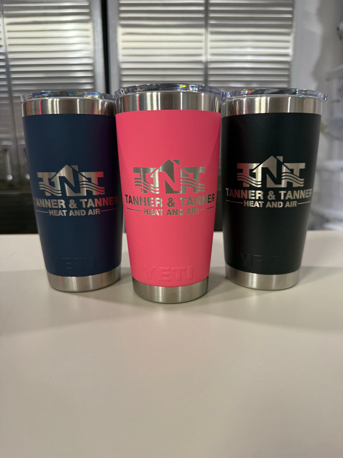 Company logo laser engraved on YETI Rambler 20 oz Tumblers in Navy, Tropical Pink and Black