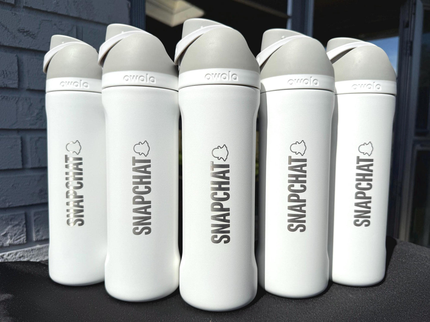 Company logo engraved on a row of white Owala FreeSip bottles