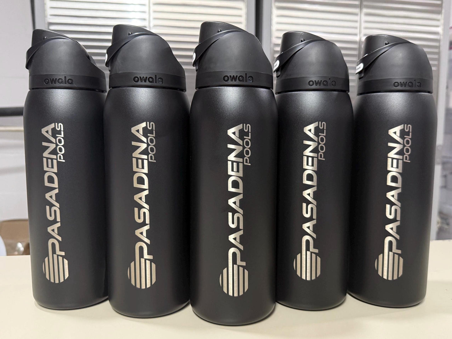 Company logo engraved on black Owala FreeSip bottles