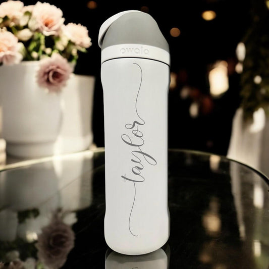 White Owala FreeSip with Taylor laser engraved in vertical Shelby script with flowing tails